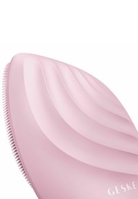 Blød lyserød silikone hårbørste med en bølget, tekstureret overflade og korte børster. "GESKE"-logoet trykt på siden.