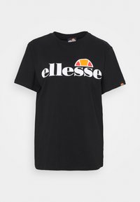 Camiseta de algodón negra con un logo blanco de "ellesse" y un gráfico en media luna naranja y amarillo encima del texto. Diseño de mangas cortas y cuello redondo.