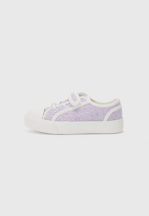 Des sneakers en toile texturée violette avec une semelle en caoutchouc blanc et un capuchon d'orteil. Présentent des lacets blancs et un détail de sangle sur le côté pour un maintien sécurisé.