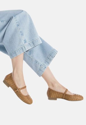 Bailarinas de cuero trenzado marrón con una correa y un pequeño tacón, combinadas con unos pantalones vaqueros recortados de mezclilla azul claro.