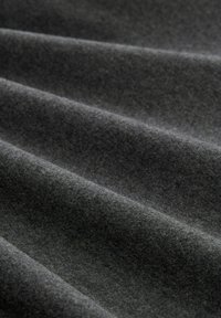 Grijze vlechtstof met een gladde textuur, die zachte golven en subtiele diepte vertoont, geschikt voor verschillende textieltoepassingen.