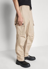 HUGO GARLO - Oldalzsebes nadrágok - medium beige