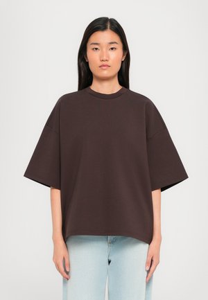 Brun oversized t-skjorte med korte ermer, rund hals, laget av et glatt stoff, kombinert med lyseblå denimjeans.