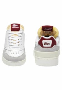 Sneakers Lacoste con tomaia in pelle bianca, dettagli in camoscio grigio, punta rotonda, dettagli perforati e logo bordeaux sul tallone.