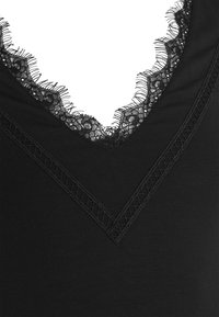 Top nero con scollatura a V caratterizzato da delicati bordi in pizzo nero e intricate ricami lungo il collo, realizzato in un tessuto morbido e liscio.
