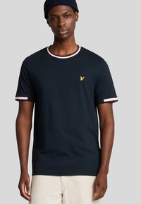 T-shirt blu navy a maniche corte, con scollatura rotonda bordata in costina e un piccolo logo di un uccellino giallo sul petto.