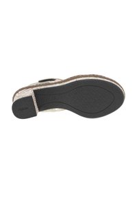 Semelle en caoutchouc noir avec motif texturé, entourée d'une base en tissu tissé de couleur beige clair, présentant un accent marron sur le bord.