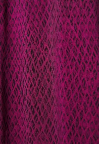 Textile featuring a textured pattern of black diamonds on a magenta background, creating a visually striking contrast with depth.