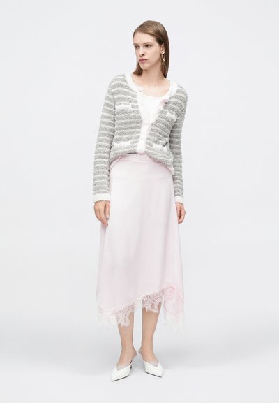 Šedý a bílý pruhovaný chlupatý kardigan, vrstvený přes růžovou saténovou sukni s krajkovým lemem, doplněný bílými mulemi s špičatou špičkou.