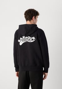 Black hoodie made of soft fabric featuring a large white "BARBOUR INTERNATIONAL" logo across the back, with a drawstring hood and ribbed cuffs.