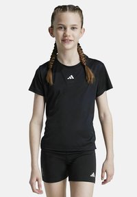 Schwarzes Sportshirt mit kurzen Ärmeln und rundem Halsausschnitt, mit einem weißen Adidas-Logo. Kombiniert mit schwarzen Shorts.