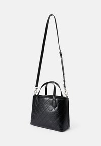 Mala acolchoada preta feita de couro, com duas alças superiores e uma alça de ombro destacável para opções de transporte versáteis.