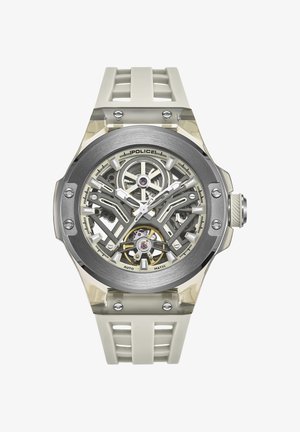 Skeletinė automatinė laikrodis su sidabro spalvos nerūdijančio plieno korpusu, skaidriu guminiu dirželiu ir sudėtinga vidine mechanika, matoma per korpusą.