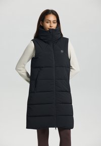 Gilet de survêtement noir avec col haut, couture horizontale, poches latérales zippées et fermeture éclair à l'avant. Petit logo sur la poitrine.