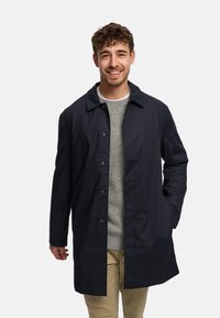 Lagana mornarska jakna s patentnim zatvaračem, špicastim ovratnikom i dva bočna džepa, nošena preko sive džemperice i bež hlača.