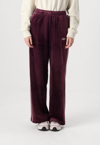 Mørke burgunder velour sweatpants med elastisk talje, med hvide sidelæg og små logo-detaljer på det ene ben.