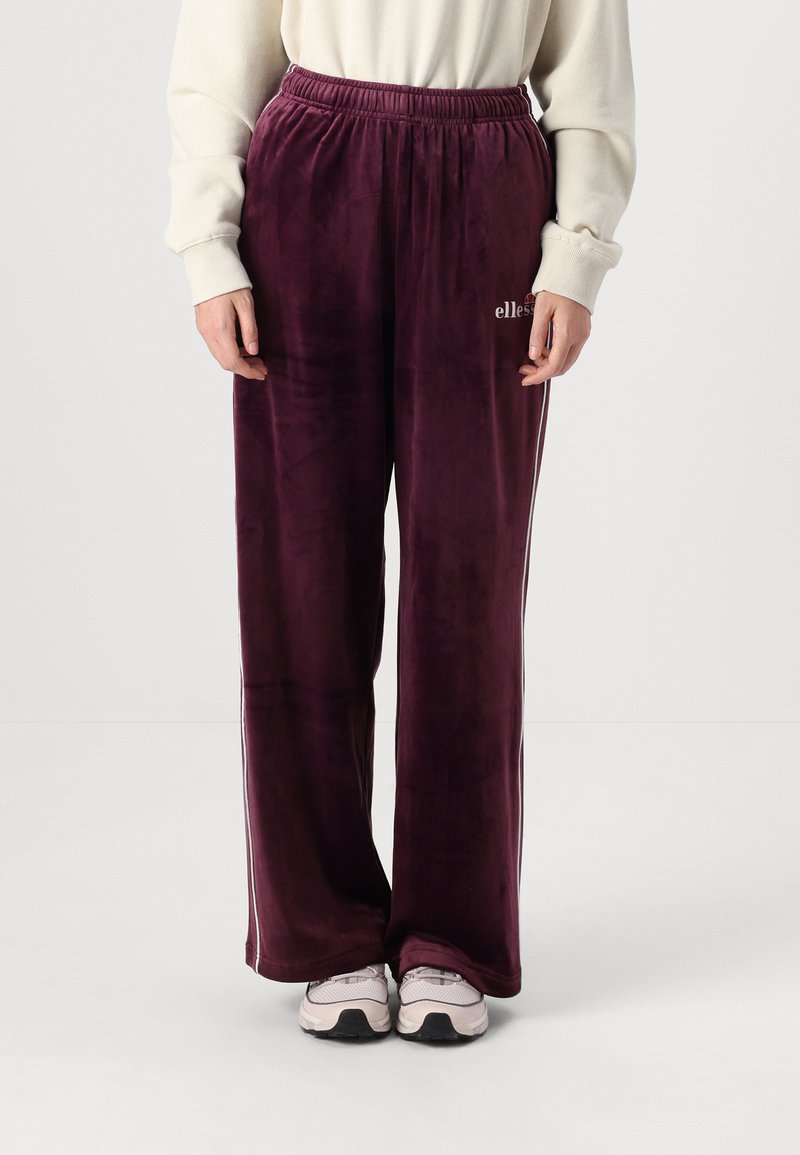 Mørke burgunder velour sweatpants med elastisk talje, med hvide sidelæg og små logo-detaljer på det ene ben.