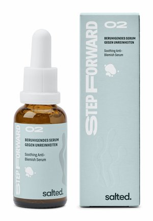 Brun glasdropperflaska med ett vitt lock, märkt "Lugnande Anti-fläck Serum", bredvid en ljusblå låda med abstrakta mönster.