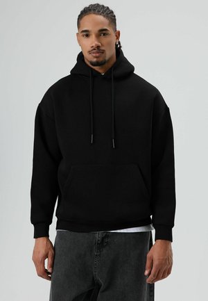 Zwarte hoodie gemaakt van fleece, met een voorvak en verstelbare trekkoorden. Losse pasvorm met geribbelde manchetten.