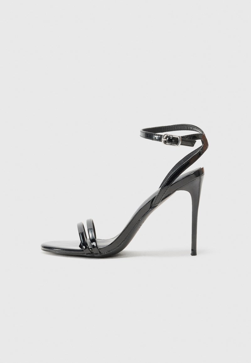 Schwarze lacklederne High-Heels-Sandalette mit dünnem Knöchelriemen, offenem Zehenbereich und zwei horizontalen Riemen an der Vorderseite. Glatte Textur.