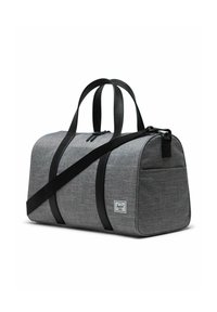 Sac de sport en tissu gris avec des poignées et des éléments en noir. Comprend une fermeture éclair et une poche avant. Patch logo sur un côté.