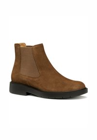 Botte cheville en suède marron avec des panneaux élastiques sur les côtés, un bout arrondi et une semelle en caoutchouc noire. Fini texturé et design minimaliste.