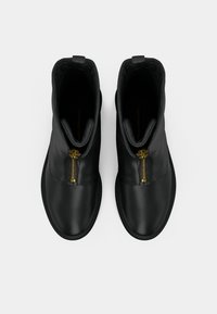 Botines negros de tobillo hechos de cuero suave, con una cremallera dorada, punta redonda y un diseño minimalista sin adornos adicionales.