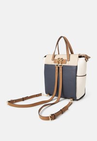 Sac à dos en cuir bicolore beige et bleu marine avec des bretelles ajustables marron et des ferrures dorées, présenté sur fond blanc.