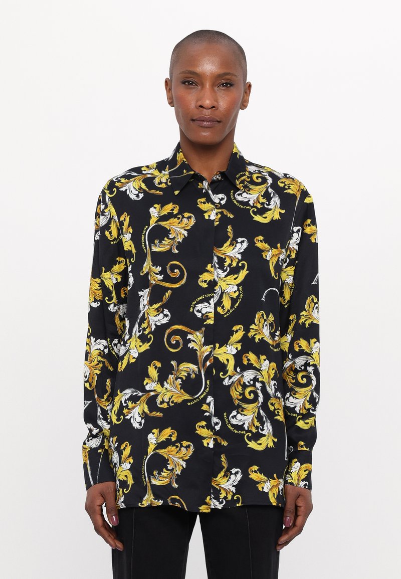 Camicia nera con motivo floreale giallo e bianco, caratterizzata da colletto, maniche lunghe e chiusura con bottoni. Tessuto morbido con vestibilità comoda.