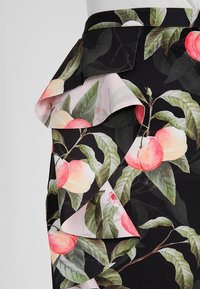 Černá sukni z látky s vrstvenými volány, která má potisk akvarelových broskví a zelených listů.