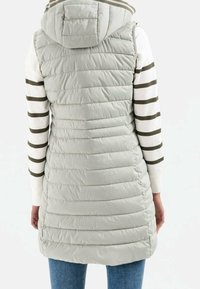 Lichtgrijze gewatteerde bodywarmer met een capuchon, voorzien van horizontale doorgestikte details en zijsplitten voor bewegingsvrijheid, gedragen over een gestreept shirt.