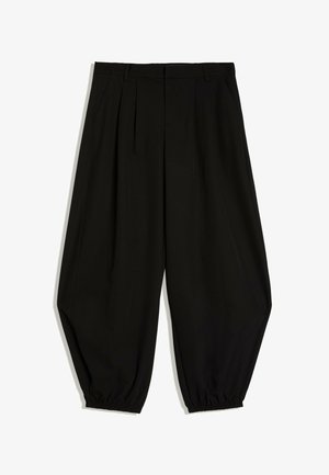 Zwarte, hooggetailleerde, taps toelopende broek met plooien, zijzakken en elastische boorden bij de enkels.