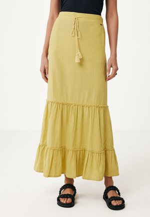Jupe maxi jaune avec un design à niveaux, fabriquée en tissu léger. Elle présente une taille à cordon et des pompons décoratifs au niveau du nœud.