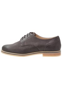 Scarpa in pelle grigia con lacci, design perforato, punta arrotondata, intersuola color sabbia e suola in gomma. Linee pulite e dettagli di cucitura a contrasto.