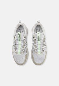 Lys grå trening sneakers med mesh-paneler, grønne detaljer og lisser. Teksturert såle med forsterket tåhette for støtte.