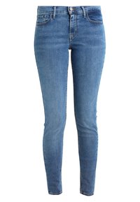 Jeans ajustados de denim azul claro, con una cintura de altura media, cinco bolsillos y un ligero desvanecimiento. Textura suave con detalles de costura a lo largo de las costuras.