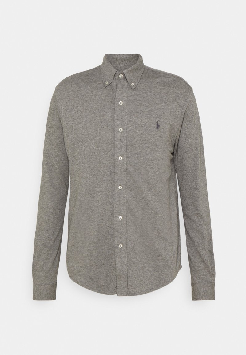 Camisa de botón de manga larga gris en una tela suave y texturizada. Presenta un cuello clásico y un pequeño logo en el lado izquierdo del pecho.