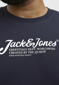 Navyblaue T-Shirt aus Baumwolle mit weißem Drucklogo: "Jack & Jones ESSENTIALS DEPT. WORLDWIDE" und "SEIT NEUNZEHNHUNDERT."