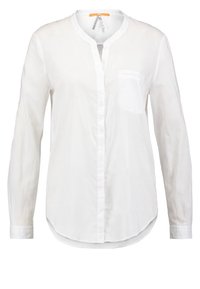 Blouse blanche à manches longues avec encolure ronde, poche avant sur la poitrine gauche et ourlet courbé.