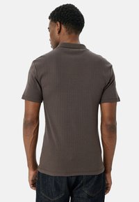 Brun ribbet polo shirt med korte ærmer, der har en klassisk krave og en subtil tekstur. Kombineret med mørke denim jeans.