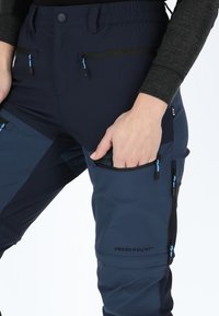 Navy outdoor pants featuring elastic waistband, zippered pockets with blue accents, and reinforced areas for durability. Brand logo visible.