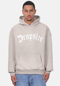 Grauer Hoodie mit einer Fronttasche, mit weißem "Dropsie"-Text. Hergestellt aus weichem Stoff, mit einer Kapuze mit Zugband und gerippten Bündchen.