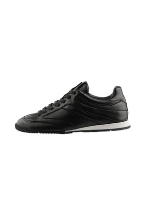 Sort lavt snøresneaker med glat læderoverdel og hvid sål set fra den indvendige side.