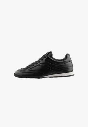 Sort lavt snøresneaker med glat læderoverdel og hvid sål set fra den indvendige side.