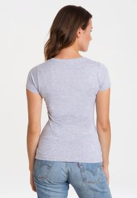 Gray short-sleeve t-shirt with a crew neck, fitted design, made from a soft material. Worn with blue denim jeans, showing a smooth texture.
