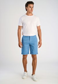 Pantaloni corti blu con risvolti, realizzati in tessuto leggero. Abbinati a una maglietta bianca semplice e sneakers bianche. Design semplice senza motivi.