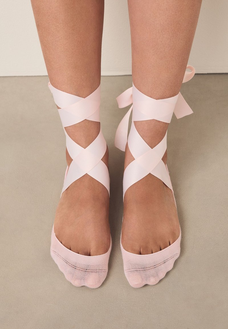 Calze rosa stile balletto con piede coperto e dita aperte, con nastri di raso incrociati avvolti intorno alle caviglie. Tessuto testurizzato, finitura liscia.