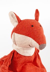 Soft toy fox with a red fabric body, cream facial accents, and stitched features. Rounded ears and a loose, textured outfit.