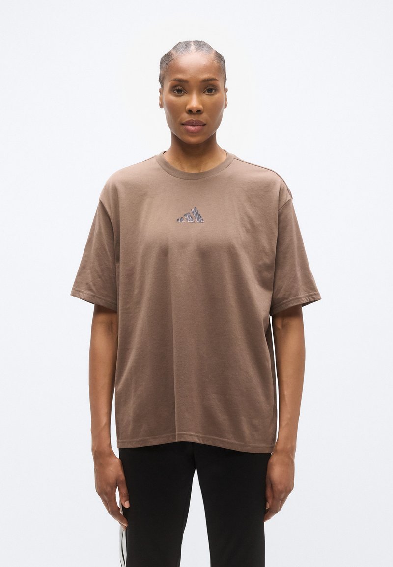 Καφέ βαμβακερό t-shirt με στρογγυλή λαιμόκοψη και άνετη εφαρμογή, με μικρό σκοτεινό λογότυπο στο στήθος και κοντά μανίκια.