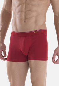 Boxer da uomo rossi realizzati in tessuto elasticizzato, con una vestibilità aderente, una vita con logo e una tasca anteriore per il supporto.